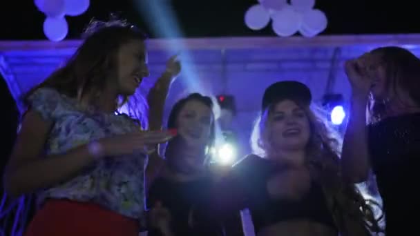 Las mujeres jóvenes bailan y las manos en alto en el club nocturno en cámara lenta, lumiere ilumina la compañía de la juventud, las niñas sonriendo — Vídeo de stock