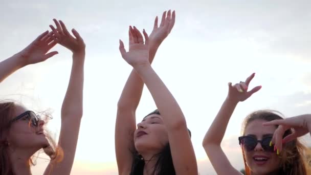 Party, młode kobiety tańczą na tle lśniącego morza, dziewczyny bawią się na brzegu, letni odpoczynek o zachodzie słońca — Wideo stockowe