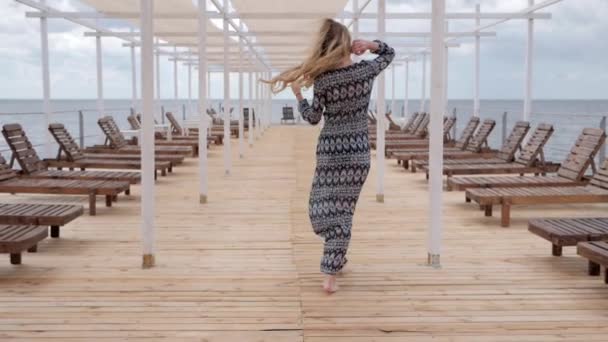 Donne a forma di camminare a piedi nudi sul molo di legno in mare, Bella donna che va a piedi nudi lungo molo, donna felice che la chiama — Video Stock