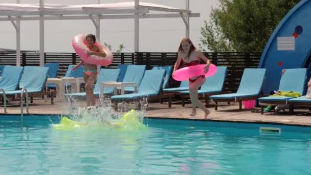 Summer party, girls resting by poolside with mattress and inflatable ring, girlfriends in bathing suit jump — Stock Video