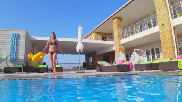 Счастливая стройная девушка в купальнике с надувные кольца погружения в бассейне в дорогом курорте во время летних каникул, подводная съемка — стоковое видео
