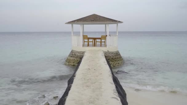 Χαλάρωση στην παραλία, μπανγκαλόου με τραπέζι και καρέκλες για ξεκούραση σε κινούμενη θάλασσα για διακοπές — Αρχείο Βίντεο