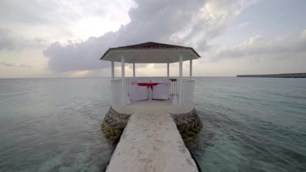 Romantischer Ausflug, Bungalow mit Gläsern und Geschirr auf Tisch am tropischen Strand gegen Wasser — Stockvideo