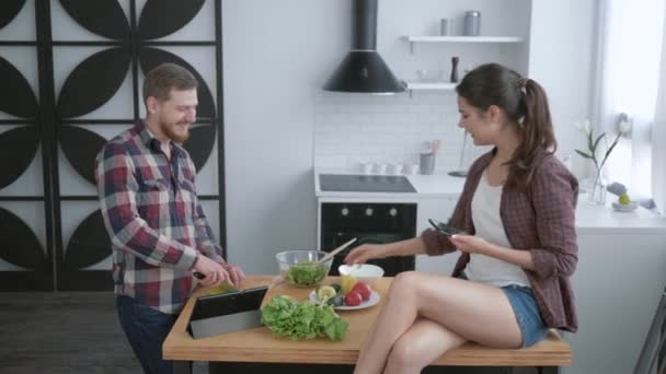 Veselý zábavný chlapec a dívka se selfie foto na mobilním telefonu a škleb při vaření zdravý zeleninový salát k snídani — Stock video
