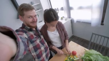 Aile yemekleri, kocasıyla mutlu bir eş telefonda selfie çektirirken mutfakta diyet planına göre, akşam yemeğinde sebzelerden sağlıklı yemekler pişirirken.