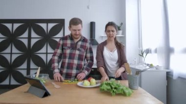 Mutfaktaki diyet planına göre sağlıklı olmak için kahvaltıda salata pişirirken kızın oynaşıp güldüğü komik bir adam.