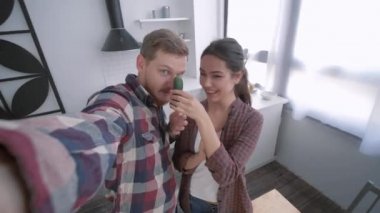 Kızlı komik adam cep telefonunda selfie videosu çekiyor ve diyete göre kahvaltıda salata pişirirken sebzelerle oynaşıyor.