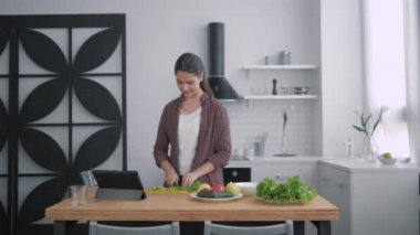 Mutfaktaki mutlu karı-koca portresi, genç aile, mutfak masasında sebzelerle brunch için video eğitimi tableti kullanarak sağlıklı bir yemek hazırlıyor.