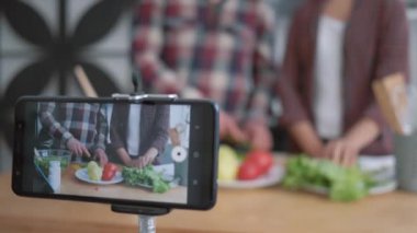 diyet planı, akıllı telefon video kaydını canlı yapıyor blogcular ve kızlar taze sebze ve sebzelerden sağlıklı yemek pişiriyorlar diyet planına göre mutfağa yakın