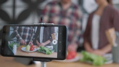 Sağlıklı beslenme blogu, cep telefonu video kaydını canlı kılıyor. Kadın ve erkekler beslenme planına göre taze sebze ve yeşilliklerden sağlıklı yemekler hazırlıyorlar.