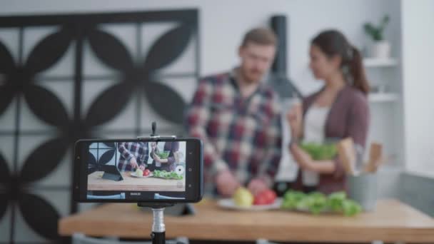 Cursos en línea para cocinar comida saludable, bloggers hombre y mujer enseñan a sus seguidores a cocinar alimentos útiles de verduras para la normalización del peso y el bienestar, mientras que los registros de teléfonos móviles video tutorial — Vídeos de Stock