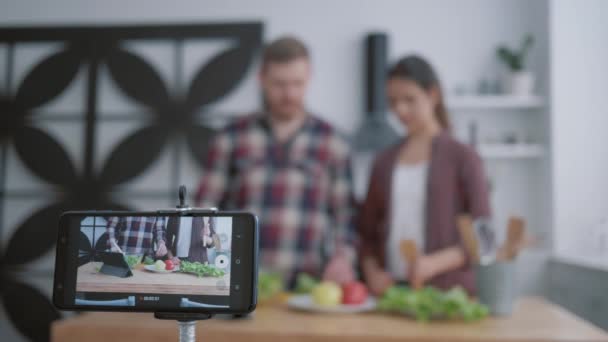 Entrenamiento en línea para cocinar alimentos útiles, bloggers chica y chico enseñar a los suscriptores a cocinar alimentos saludables de verduras para la normalización del peso y el bienestar, mientras que los registros de teléfonos móviles video tutorial — Vídeos de Stock