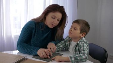 Eğitim görme engelli çocuklar için, anne kör oğula kör karakterler yazmayı öğretiyor yazı tipi parlak odada oturuyor.