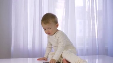 Parlak odada akıllı telefonla güzel bir erkek bebek oynanır.