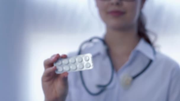 Píldoras en la mano del médico femenino sobre fondo blanco en desenfocado — Vídeos de Stock