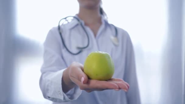 Especialista profissional em alimentos com maçã verde nas mãos dá em câmera aconselhando dieta saudável para o bem-estar, sem foco — Vídeo de Stock