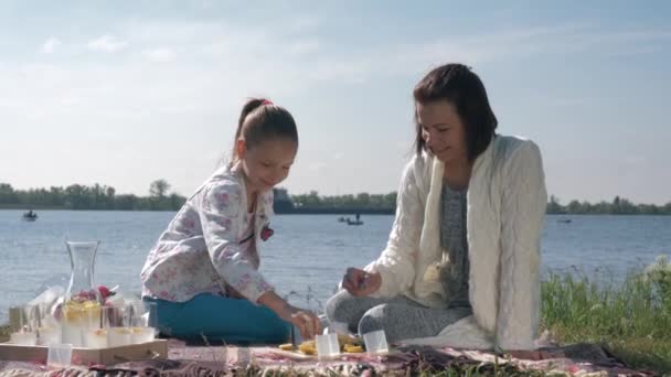 Vztah matka-dítě, šťastná žena s dcerou se navzájem krmí během odpočinku na rodinném pikniku na trávníku — Stock video