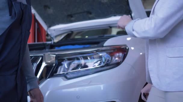 Mujer consumidor da llaves del coche al mecánico auto para la reparación y da la mano en la estación de servicio — Vídeo de stock