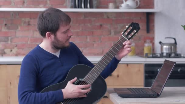 Grappig instrumentalist man leren spelen gitaar maakt gebruik van laptop computer met online video training en genieten van muziek — Stockvideo