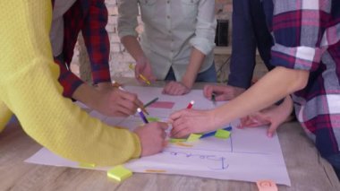 Başarılı koç eğitimi, yaratıcı ofis işbirlikçileri yeni proje geliştirme fikrinin zaferi sırasında modern ofiste renkli çıkartmalı büyük kağıt üzerinde alkışlıyorlar.