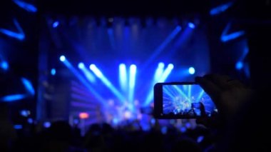 Akıllı telefonlu hayranların kolları gece sahne ışıkları altında rock konserinde fotoğraf ve video kaydı yapıyor.
