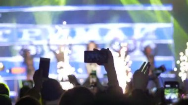Cep telefonlu hayranların elleri, akşamları sahne ışıklarında rock festivalinde fotoğraf ve video kaydı yapıyor.