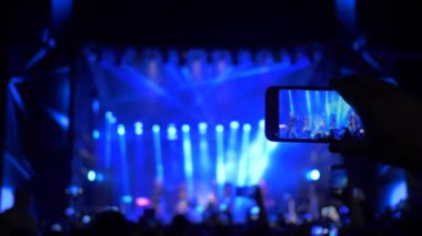 Rock müzik etkinliği, ellerinde akıllı telefonuyla kalabalık hayranları akşam saatlerinde rock etkinliğinde canlı yayında eğlenirken ve hatıralar için video çekerken.