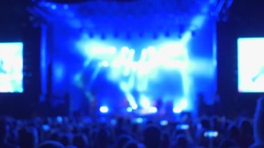 Rock partisi, odaklanmamış hayran kalabalığı akşam vakti aydınlık sahne önünde canlı müzik konserinin keyfini çıkarın.