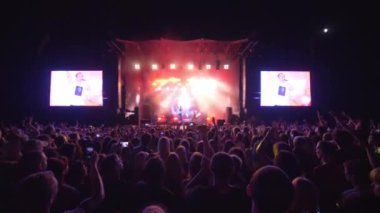 Birçok insan cep telefonlarıyla gece büyük ekranlı parlak sahnelere karşı rock canlı müzik konserinde video kaydetmeyi ve eğlenmeyi sever.