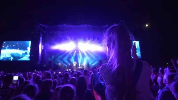 Rockconcert, veel fans genieten en klappen op live muziekfeest tegen fel verlicht podium met grote schermen 's nachts — Stockvideo