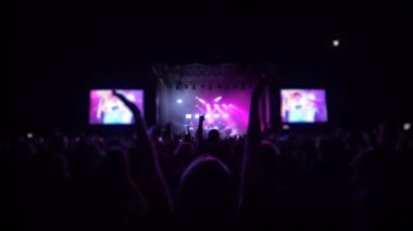 Konser partisi, seyirci kalabalığı rock festivalinde zıplıyor ve el çırpıyor ışıklar altında telefonlar