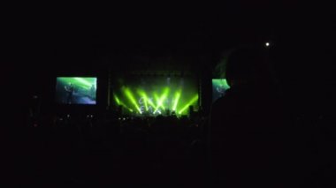 Canlı müzik etkinliği, omuzlarında oturan kız silueti kalabalığa karşı karanlık sahnenin önünde rock konserinin keyfini çıkarıyor.