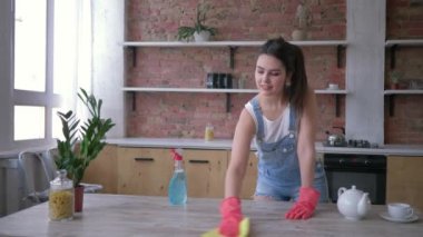 Ev işleri, lastik eldivenli mutlu hizmetçi kız temizlik için tozlu mobilyaları temizleyiciyle ovuyor.