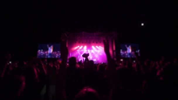 Actieve fans genieten van live muziek en springen tijdens rockconcert in fel licht in Slow motion — Stockvideo