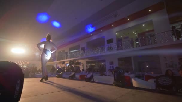 Moda defilesi, podyum mankeni mayo giyen kız podyumda yürüyor parlak spot ışıklarıyla yeni koleksiyonun sunumunda — Stok video