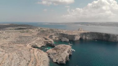 Pahalı bir dinlenme yeri, deniz lagününün üst manzarası kayalık kıyılarda turkuaz su üzerinde beyaz yatlar.