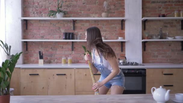 快乐的家务活，有趣的家庭主妇在做家务活的时候像麦克风一样用扫帚唱歌 — 图库视频影像