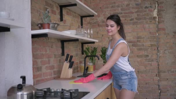 Maison de nettoyage général, fille heureuse femme de ménage dans des gants en caoutchouc pour nettoyer essuyer les meubles poussiéreux sur la cuisine — Video