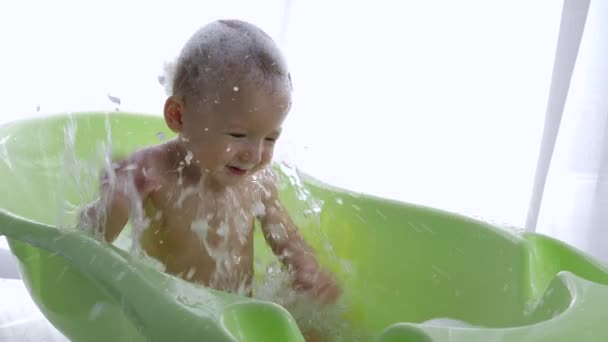 Zvědavý batole je jíst mýdlo sudy při koupání ve vaně ve světlé místnosti — Stock video