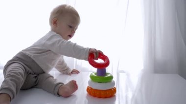 Bebek gelişimi, tatlı çocuk parlak odada eğitici oyuncak piramidiyle oynanıyor.