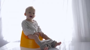 Çocuklar hijyen, mutlu bebek lazımlığa oturuyor ve gülümsüyor.