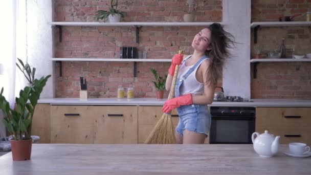 Домашняя рутина, радостная домработница танцует и поет в босоне, как микрофон во время домашних обязанностей — стоковое видео