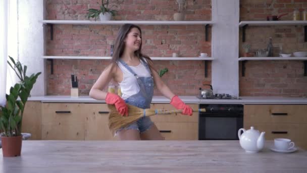 Alegre casa limpeza, alegre governanta fêmea com vassoura joga como guitarra durante as tarefas domésticas — Vídeo de Stock