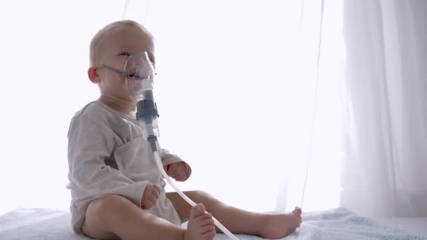 Procedimiento de inhalación, niño precioso respira a través de nebulizadores para Trata la inflamación de las vías respiratorias en habitación luminosa — Vídeo de stock