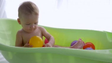 Çocuklar hijyen, parlak odada yüzerken renkli toplarla oynayan tatlı bir çocuk.