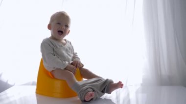 Küçük duygusal çocuk Chamberpot 'ta oturuyor ve gülüyor.