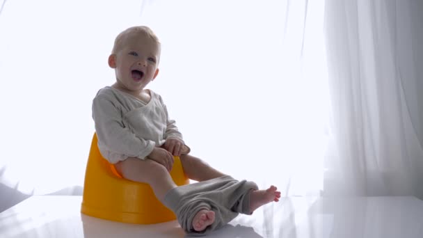 Klein emotioneel kind jongen zitten op kamerpot en lacht in heldere kamer — Stockvideo