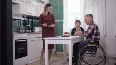 Mutlu engelli baba yemek pişirirken ailesiyle mutfakta eğleniyor.