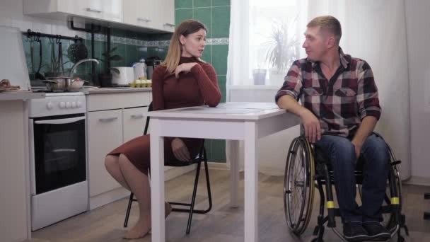 Стресова ситуація, інвалід в інвалідному візку пригнічується під час сварки з нервовою дружиною, прокляття і махаючи руками в нещасливій сім'ї на кухні — стокове відео