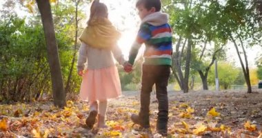 İlk aşk, kız, parkta sarı yaprakların arkasında el ele tutuşan adamla yürür.